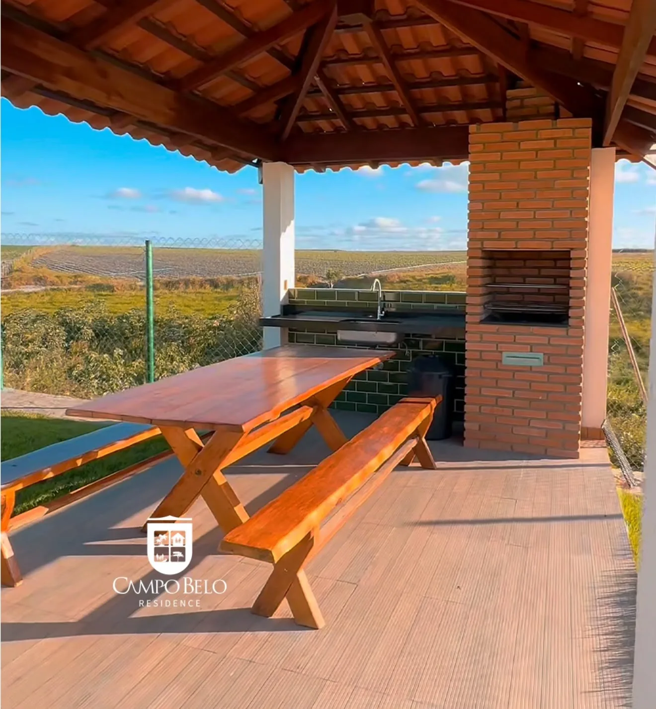 Espaço Gourmet com churrasqueira de tijolinho e mesa de madeira